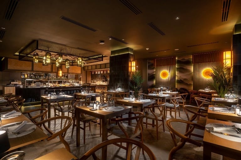 Upscale restaurant interior with wooden tables and chairs, warm ambient lighting, bar counter, and Asian-inspired decor elements